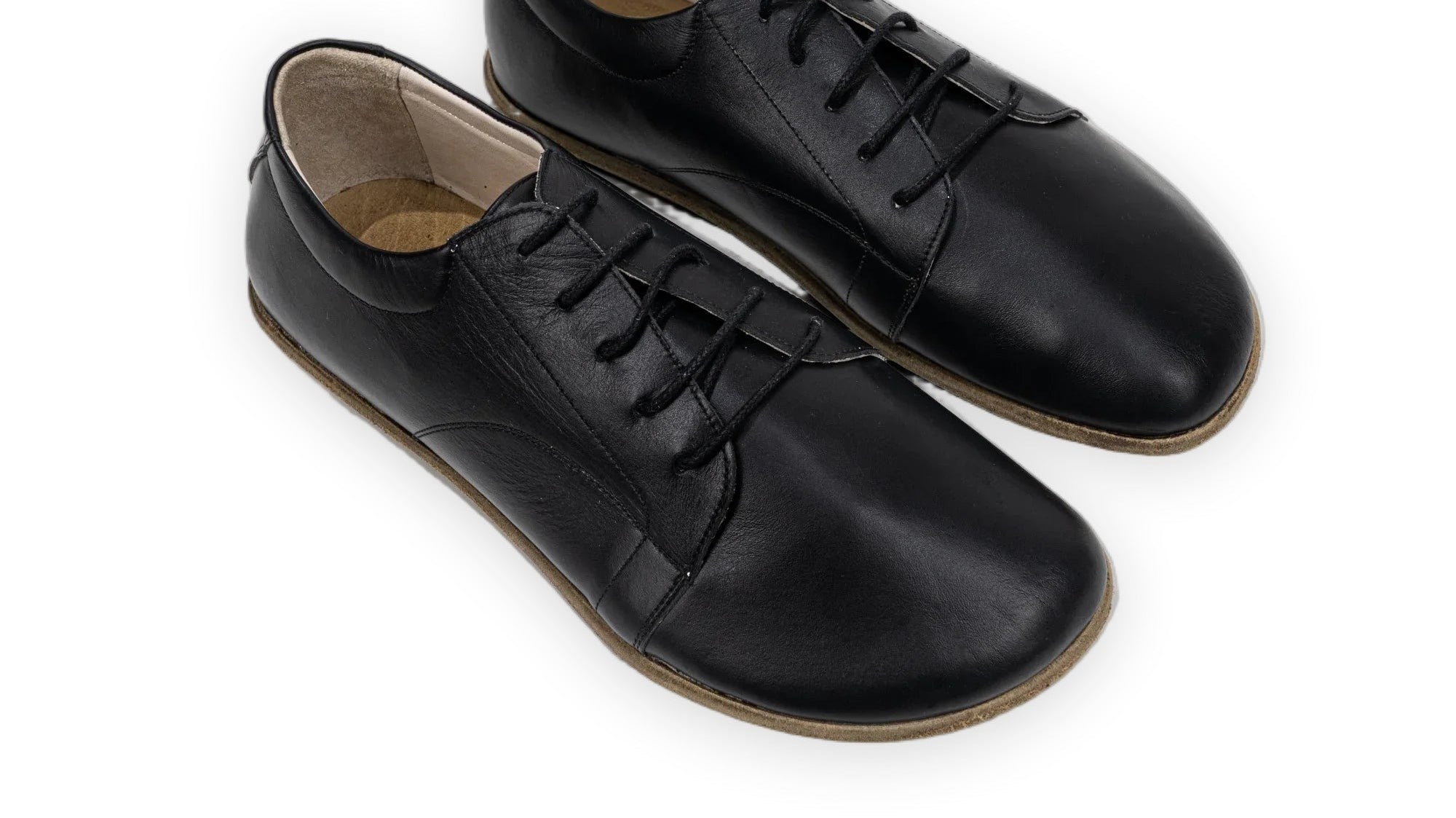 Black full-grain leather barefoot sneakers with a wide toe box, packed as versatile travel shoes