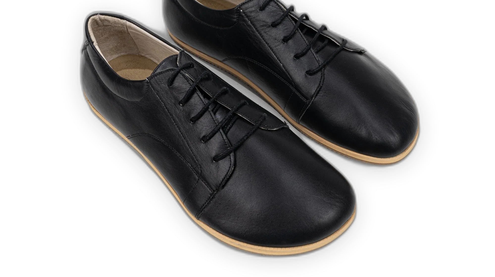 Black full-grain leather barefoot sneakers with a wide toe box and zero drop sole, worn daily to build foot strength