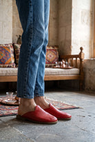 Person in light jeans wearing red leather shearling slippers by Bespoky in a traditional stone room with kilim cushions in Gaziantep