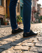 Black barefoot Oxford shoes worn on a cobblestone street in Balat, Istanbul (AI-assisted background, real Bespoky product) [S1-balat-oxford_v1.png]