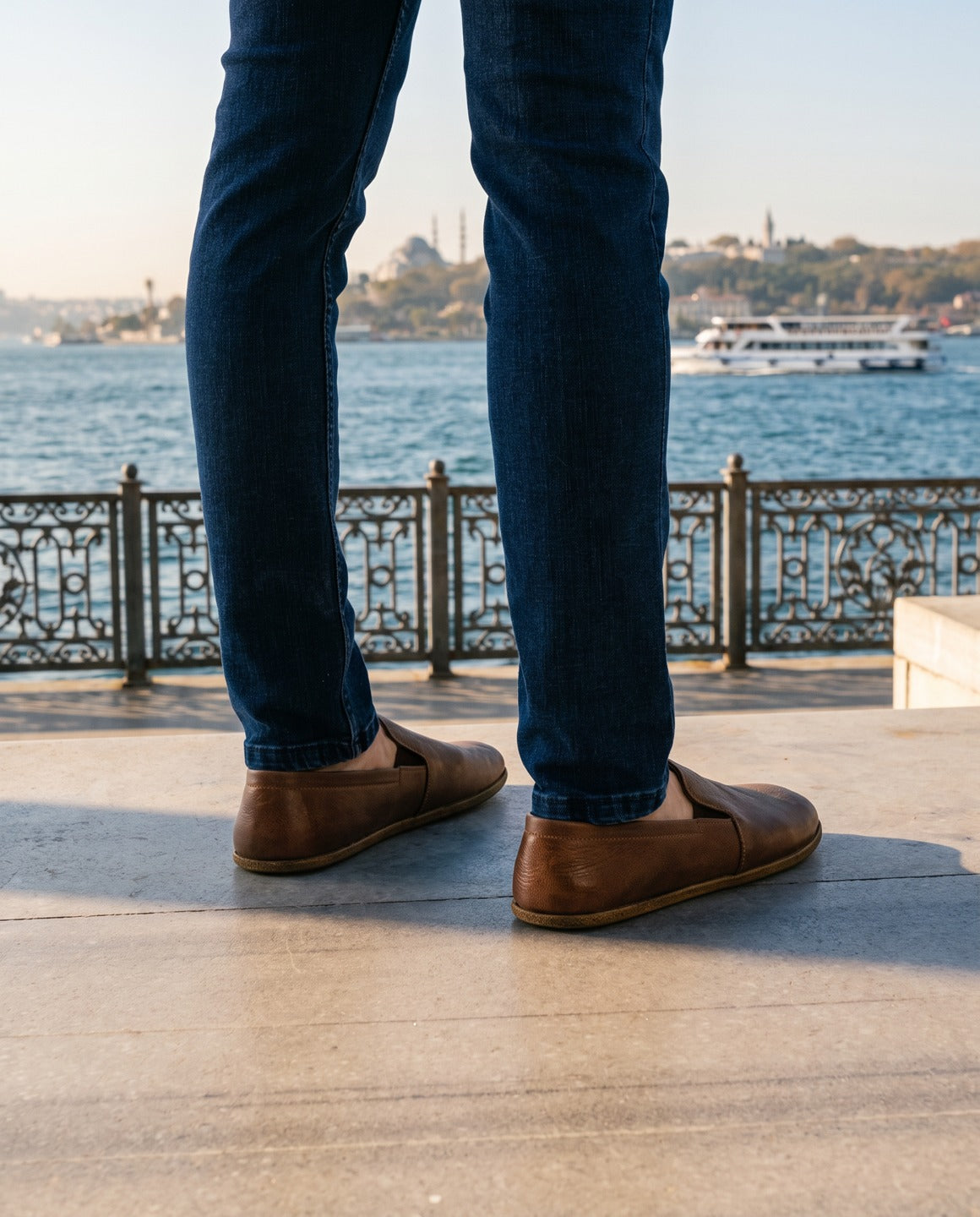 Men's brown barefoot shoes on the Bosphorus waterfront in Istanbul (AI-assisted background, real Bespoky product) [S5-bogaz-eminonu_v1.png]