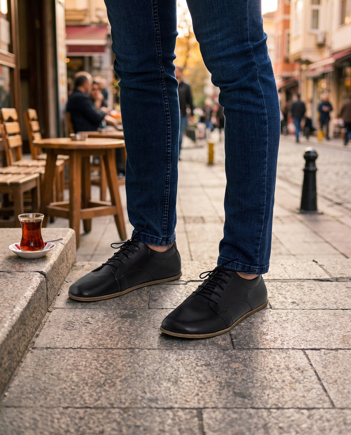 Men's black barefoot leather sneakers outside a cafe in Kadikoy, Istanbul (AI-assisted background, real Bespoky product) [S6-kadikoy-taksim_v1.png]