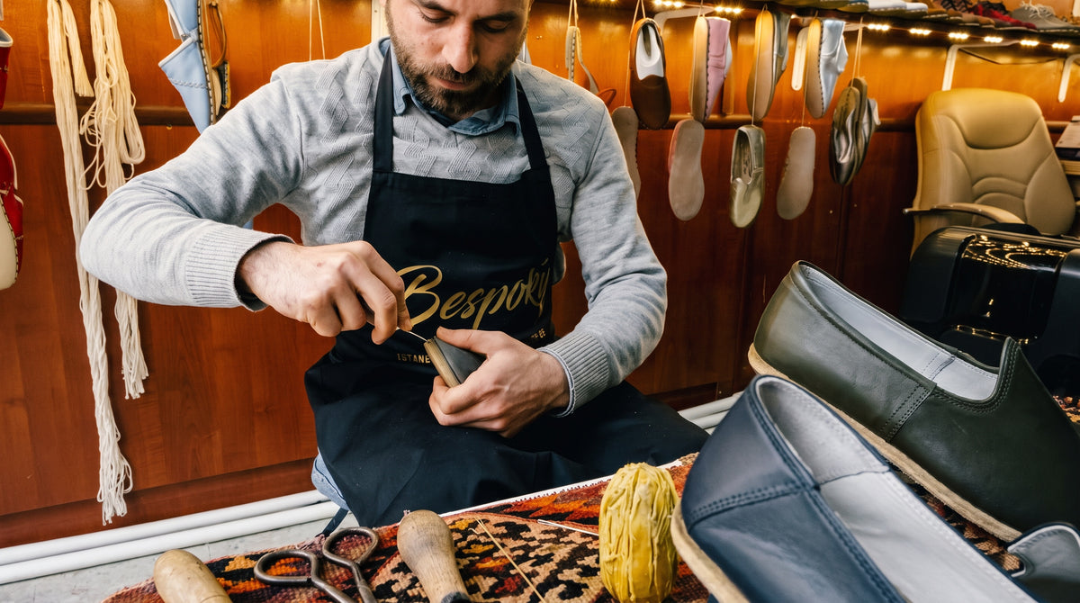 Bespoky craftsman stitching a leather shoe at his workbench
